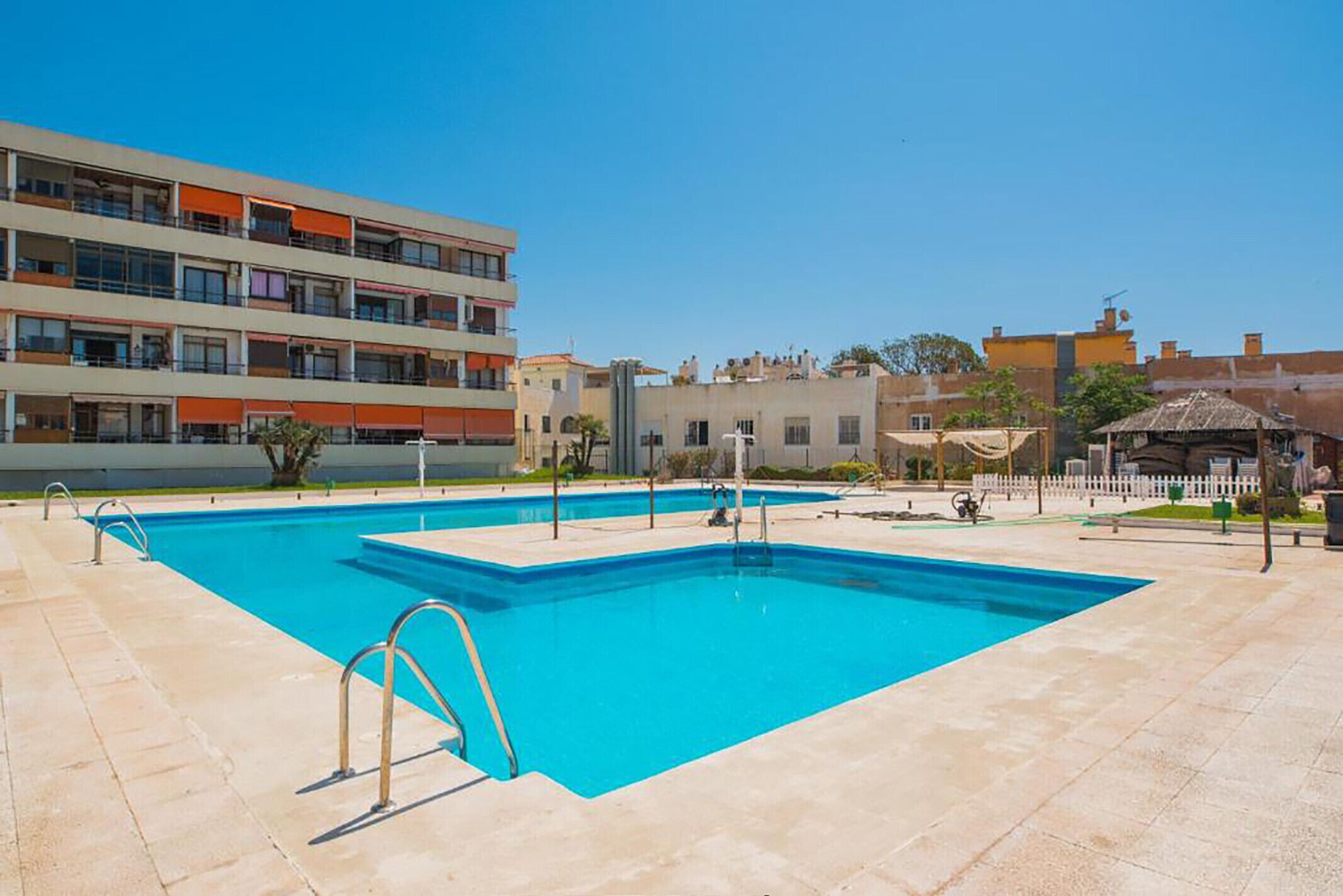 A swimming pool with a clear blue water, surrounded by a tiled deck.