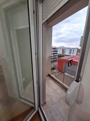 A view from a balcony with a glass door leading to a room. - Modern 1 bedroom - Free Street Parking - Self Check In - AC (Podgorica)