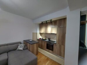 Un espace de vie compact comprenant un coin cuisine, un canapé et une petite table.