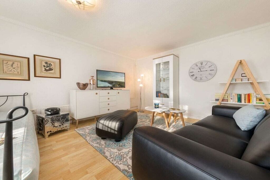 A modern living room with a sofa, a small table, a television, and a bookshelf.