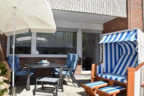 An outdoor patio with a table, chairs, and a striped sofa. - Holiday apartment with 1 bedroom (Norden)