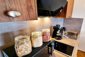 Eine Küche mit einem schwarzen Herd, einer Kaffeemaschine und zwei Glasbehältern auf der Arbeitsplatte.