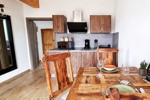 Een keuken met houten kastjes, een aanrecht en een eettafel met stoelen.