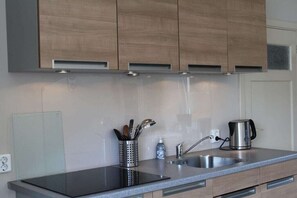 Eine moderne Küche mit Spüle aus Edelstahl, einem Wasserkocher und Holzschränken.