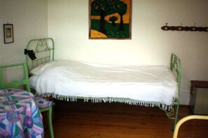 A single bed with a green metal frame, a white mattress, and a colorful quilt on a small table beside it. - Holiday home with 1 bedroom (Wutach- Münchingen)