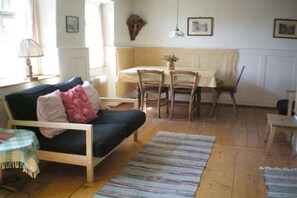 A cozy living room with a sofa, a dining table, and chairs. - Holiday home with 1 bedroom (Wutach- Münchingen)