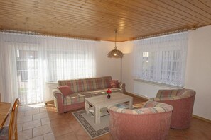 Ein Wohnzimmer mit Holzboden, einer Couch, einem Couchtisch und einer Stehlampe.