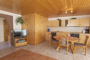 Eine Küche mit Holzwandverkleidung, einer Essecke, einem Fernseher und einem Geschirrspüler.