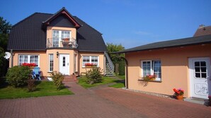 A two-story house with a balcony, a front door, and a small garden area. - Holiday apartment in Alt-Reddevitz with Wi-Fi (Alt-Reddevitz)