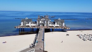 A pier extending into the sea with a building at the end, a sandy beach, and a clear sky. - Holiday apartment in Alt-Reddevitz with Wi-Fi (Alt-Reddevitz)