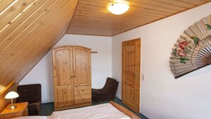 A bedroom with a wooden ceiling, a bed, a wardrobe, a chair, and a wall-mounted fan. - Holiday apartment in Alt-Reddevitz with Wi-Fi (Alt-Reddevitz)
