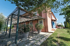 Ein Haus mit überdachter Terrasse, Blumentöpfen und einer blauen Tür.