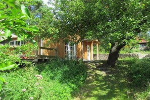 A rustic wooden house with a large tree in front, surrounded by lush greenery. - Lakeside idyll Comthurey - Reed House (Wokuhl-Dabelow OT Comthurey)