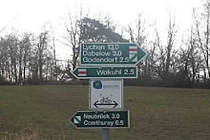 A directional sign with multiple destinations and distances. - Lakeside idyll Comthurey - Reed House (Wokuhl-Dabelow OT Comthurey)