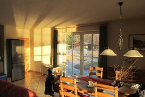 A dining area with a table and chairs, a refrigerator, and a window with a view of the outdoors. - Lakeside idyll Comthurey - Reed House (Wokuhl-Dabelow OT Comthurey)