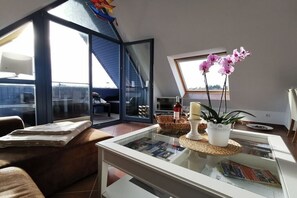 Een moderne woonkamer met een glazen salontafel, een bank en uitzicht op buiten.