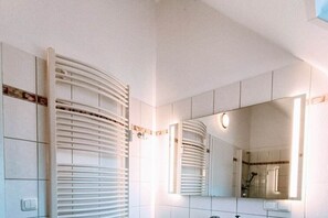 Een badkamer met een grote spiegel, een handdoekhouder en een douche.