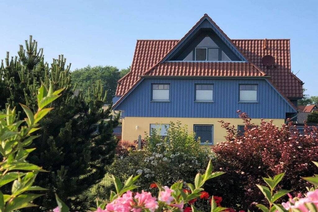 Ein zweistöckiges Haus mit rotem Ziegeldach und blauer Fassade.