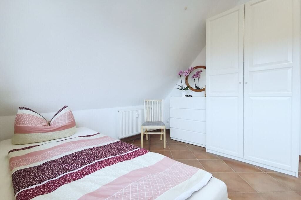 Un dormitorio con cama, una silla, armario y radiador.