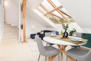 Ein modernes Schlafzimmer im Loft-Stil mit Dachfenster, einem Essbereich mit Tisch für zwei Personen und einer Treppe.