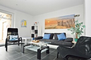 A modern living room with a sofa, two armchairs, a coffee table, and a bookshelf. - Holiday apartment with 2 bedrooms (Norden)