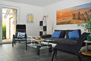 Ein modernes Wohnzimmer mit einer Couch, Sesseln, einem Couchtisch und einem Bücherregal.