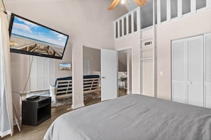 A bedroom with a bed, a television mounted on the wall, and a view of a beach through the window. - Glenn's Bay Retreat Surfside Beach (Surfside Beach)