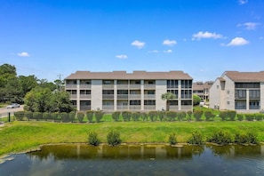 A multi-story residential building with balconies, a grassy area in front, and a body of water. - Glenn's Bay Retreat Surfside Beach (Surfside Beach)