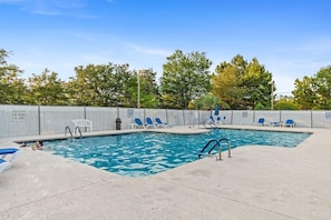 A swimming pool with blue water, surrounded by a fence, and several lounge chairs. - Glenn's Bay Retreat Surfside Beach (Surfside Beach)