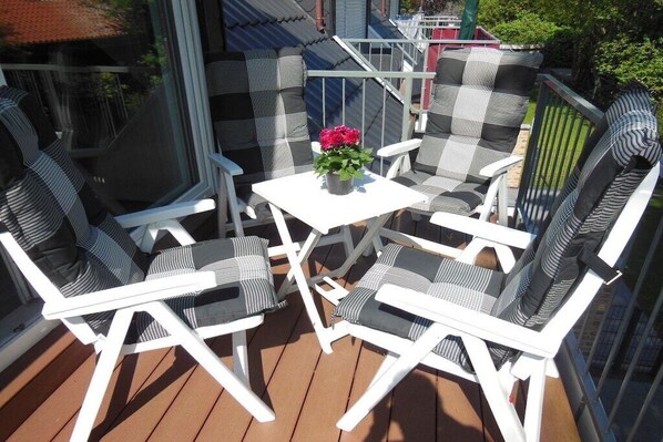 A deck with white furniture and a table with a flower centerpiece. - Holiday apartment with 2 bedrooms (Norden)