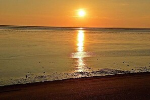A beach scene with a sunset over the ocean. - Holiday apartment with 2 bedrooms (Norden)