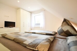 A bedroom with a bed, a television on a stand, and a window with curtains. - Holiday apartment with 2 bedrooms (Norden)