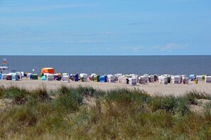 Une plage avec de nombreuses cabanes de plage colorées et quelques parasols.