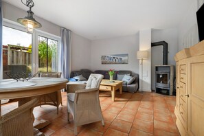 Una sala de estar con comedor, un conjunto de sofás, una chimenea y vistas a través de una ventana.