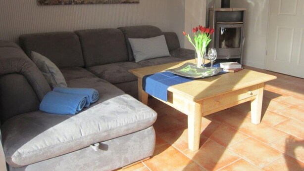 A living room with a sofa, a coffee table, a lamp, and a painting on the wall. - Apartment 'Anna Sandbank' with Private Terrace, Private Garden and Wi-Fi (Krummhörn)