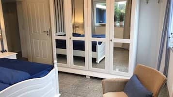 Une chambre à coucher comprenant un lit, une chaise et une armoire aux portes miroir.