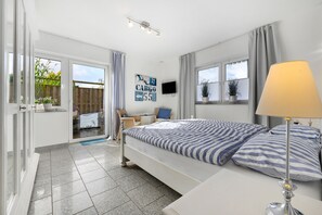 Un dormitorio con cama, lámpara de noche, televisión y vistas al exterior.