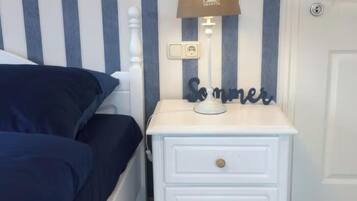Une chambre à coucher avec un lit, une table de chevet avec une lampe et un mur à rayures verticales.