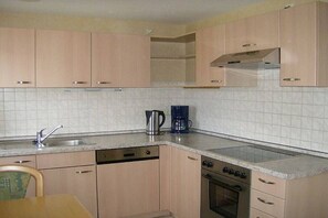 A kitchen with light-colored cabinets, a dishwasher, an oven, and a coffee maker on the countertop. - Holiday home with 1 bedroom (Eisenbach-Schollach)