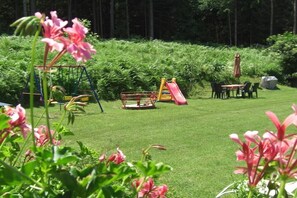 A well-maintained garden with a swing set, a slide, and a dining area with chairs and a table. - Holiday apartment with 1 bedroom (St. Kanzian\/Klopeinersee)