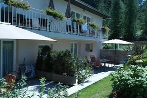 A two-story building with a balcony, outdoor seating, and a garden area. - Holiday apartment with 1 bedroom (St. Kanzian\/Klopeinersee)