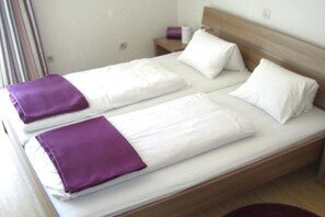 A double bed with white linens and purple accents, a wooden headboard, and a small bedside table with a purple object. - Holiday apartment with 1 bedroom (St. Kanzian\/Klopeinersee)