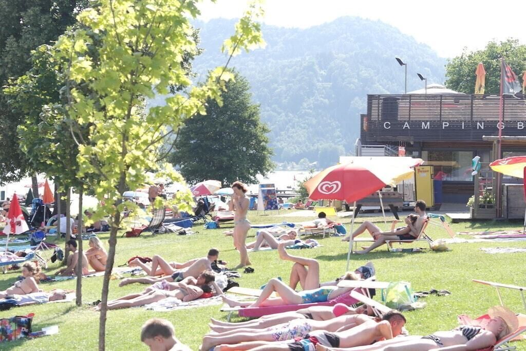A campground with tents and people relaxing on the grass.