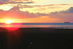 Ein Sonnenuntergang über einem Gewässer, in der Ferne ein Schiff.