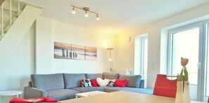 Ein modernes Wohnzimmer mit einem grauen Sofa, einem Couchtisch und einer Treppe.