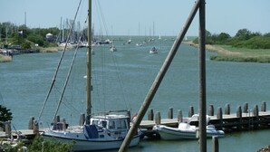 A marina with multiple boats docked, a clear sky, and calm water.