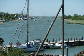 Un port de plaisance où sont amarrés de nombreux bateaux, un ciel dégagé et une eau calme.