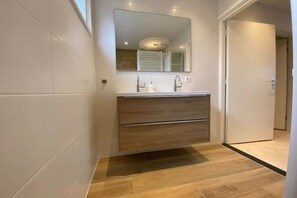 A modern bathroom with a wooden vanity, a large mirror, and a tiled floor. - Cabin in Makkum with swimming pool (Makkum)
