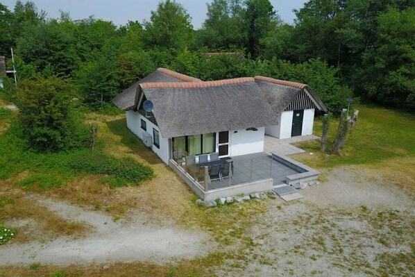 A single-story house with a thatched roof, a covered porch, and a small garden area. - Cabin in Makkum with swimming pool (Makkum)
