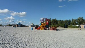A sandy beach with a playground featuring slides and climbing structures.